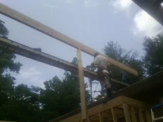 Carpenter setting a ridge beam over a new addition frame — Ice Dam Removal by Roofing Brothers in Monaca