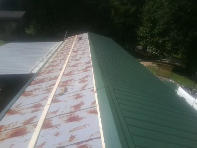 Old rusted panels beside newly installed green metal roofing — Wind Damage Roof Repair by Roofing Brothers in Monaca