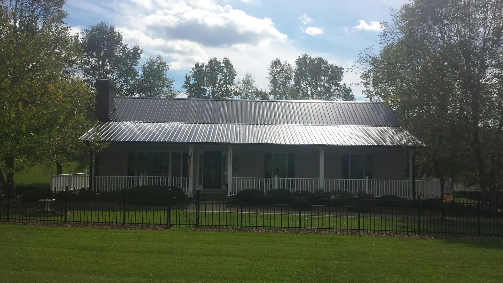 Gray metal roof on a brick ranch with a full width front porch — Gutter Guard Installation work by our crew in Monaca