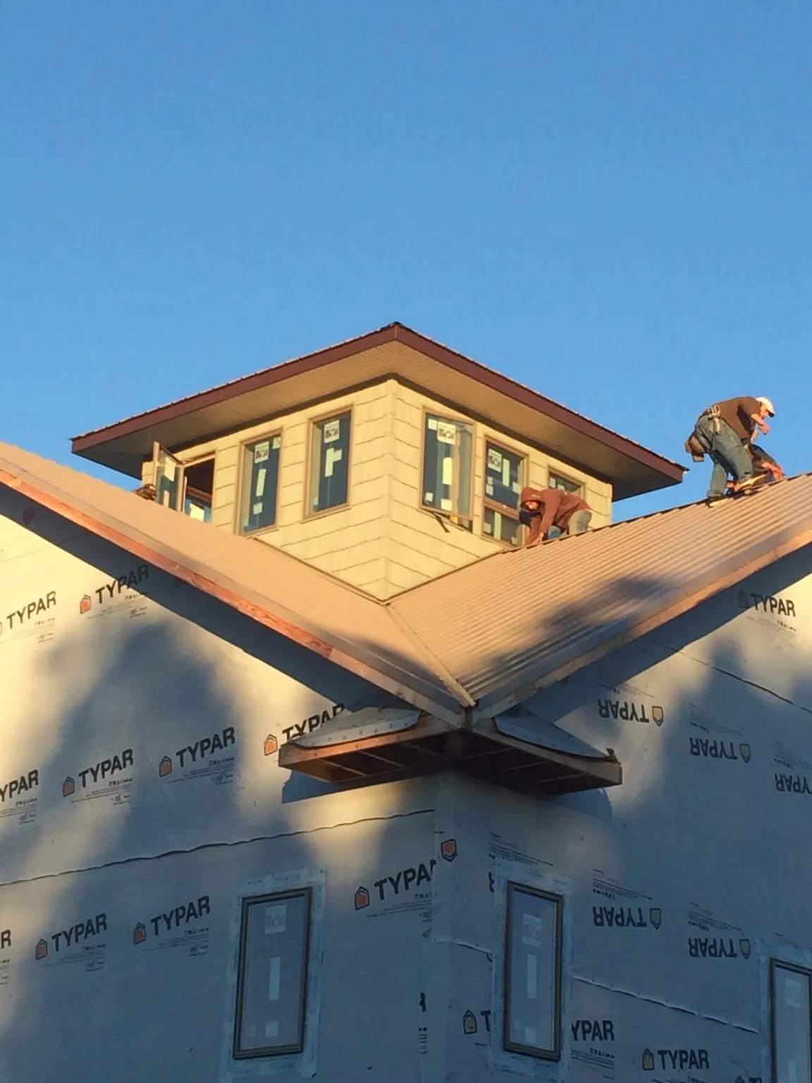 Roofers working around a rooftop cupola on a new metal roof at sunset — Roof Waterproofing in Monaca by Roofing Brothers